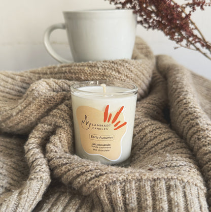 Early Autumn dual-scented soy candle by Flammart with White Cashmere and Hot Chocolate notes styled on a cozy knit sweater